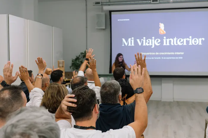 Participantes levantan la mano durante un encuentro, ante la presentación de Mi Viaje Interior